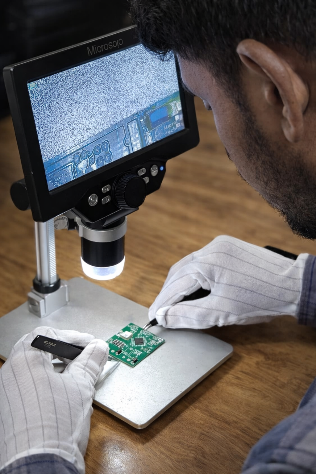 Engineer inspecting circuit board under a digital microscope